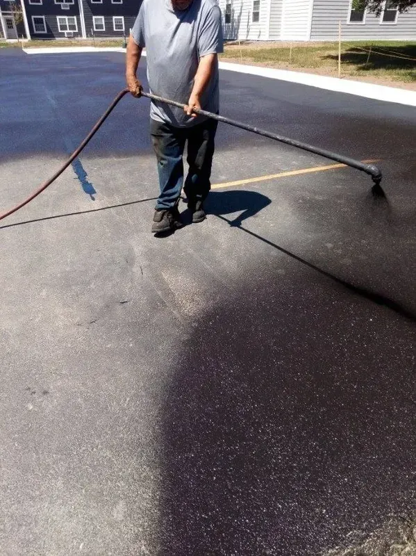 A man is spraying asphalt with a hose