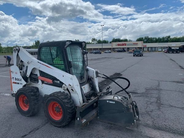 A bobcat is parked in a parking lot in front of a store.