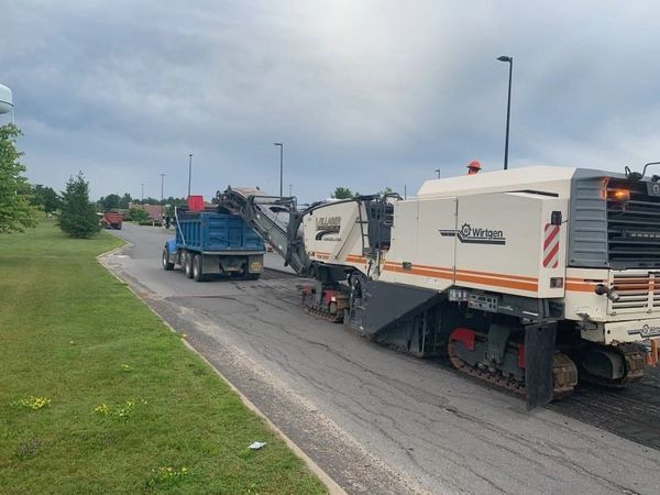 A truck is driving down a road next to a large machine.