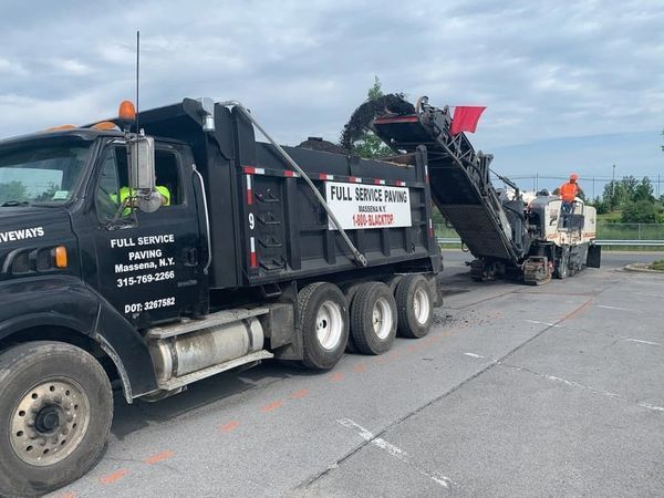 A dump truck is parked in a parking lot next to a machine.