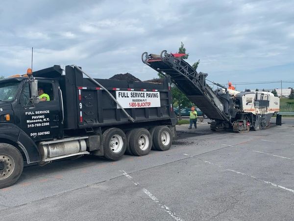 A dump truck is parked in a parking lot next to a machine.