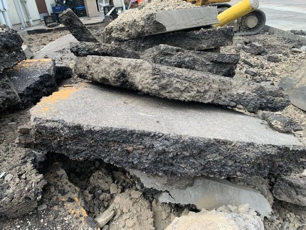 A pile of concrete is sitting on the ground next to a yellow shovel.