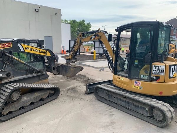 Two excavators are parked next to each other in a parking lot.