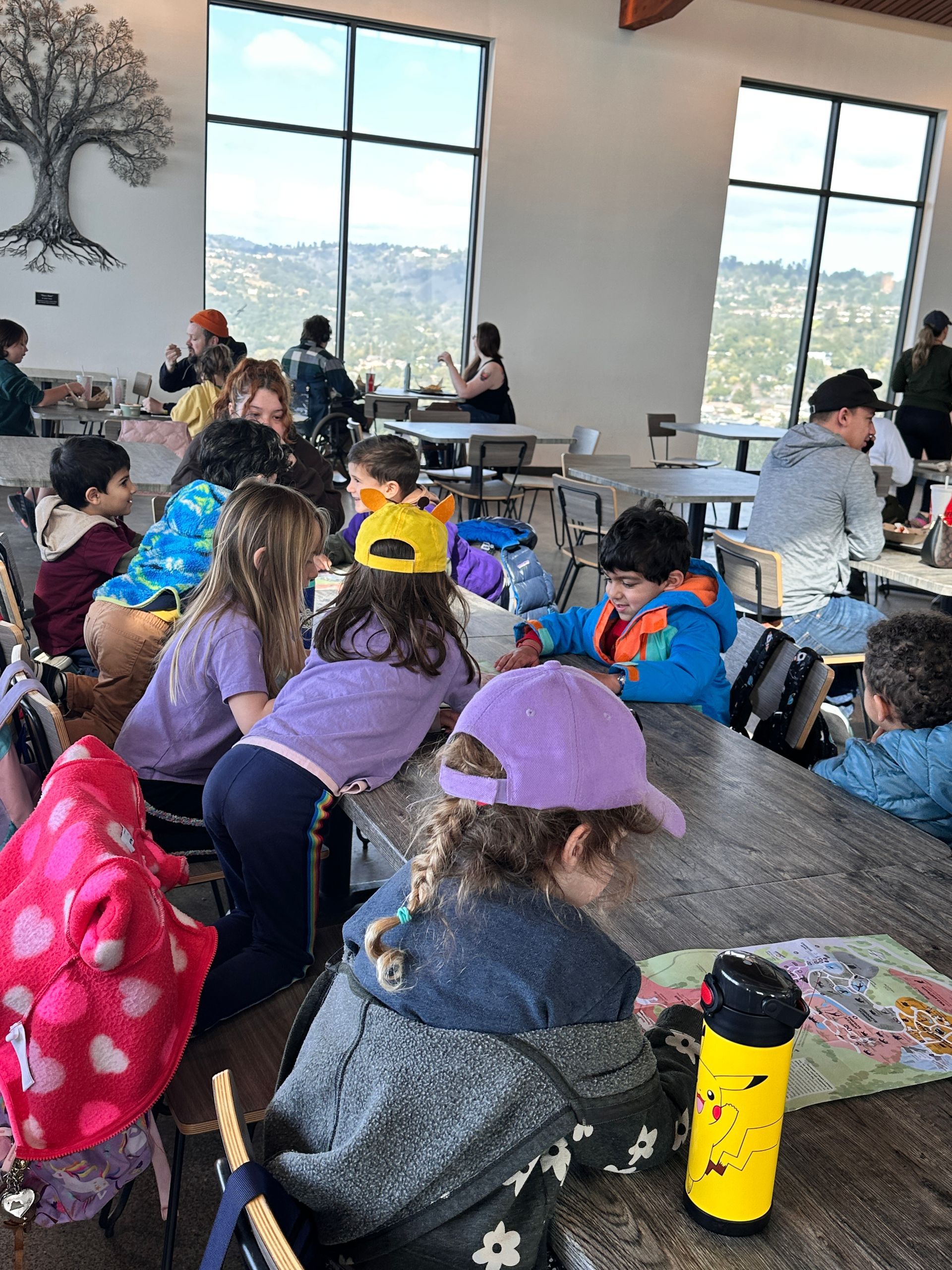 A group of Montessori child are sitting at tables in a restaurant at the Oakland Zoo.