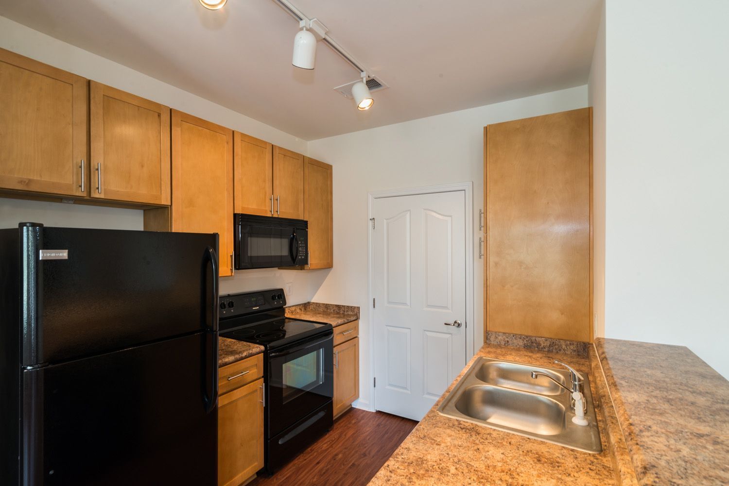 Kitchen with dark cabinets, stainless steel appliances, breakfast bar, and small dining table.