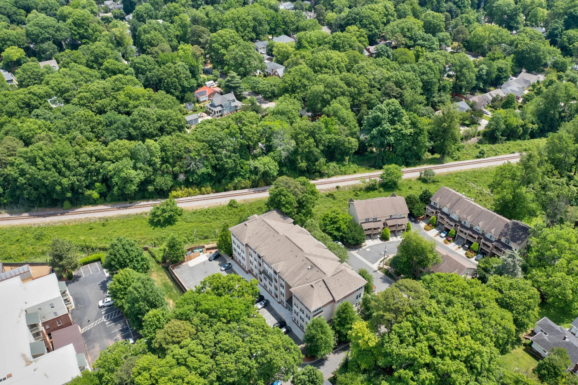 Aerial view of residential community surrounded by trees and a railway line.