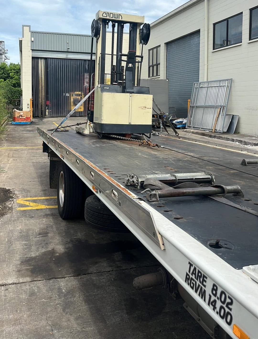Forklift on a Flatbed Trailer Outside an Industrial Building — A B & Forge Towing In Redcliffe, QLD