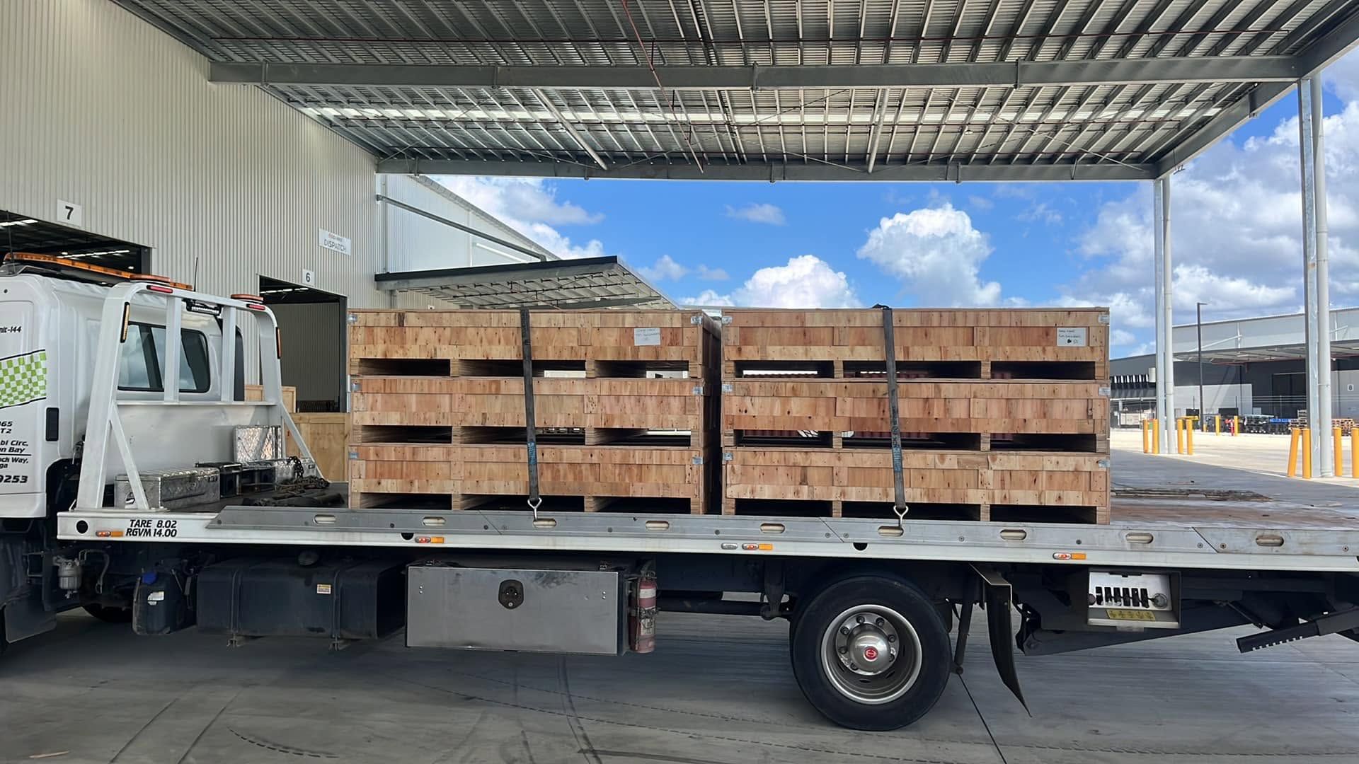 Flatbed Truck Loaded With Stacked Wooden Crates Under a Metal Canopy — A B & Forge Towing In Morayfield, QLD