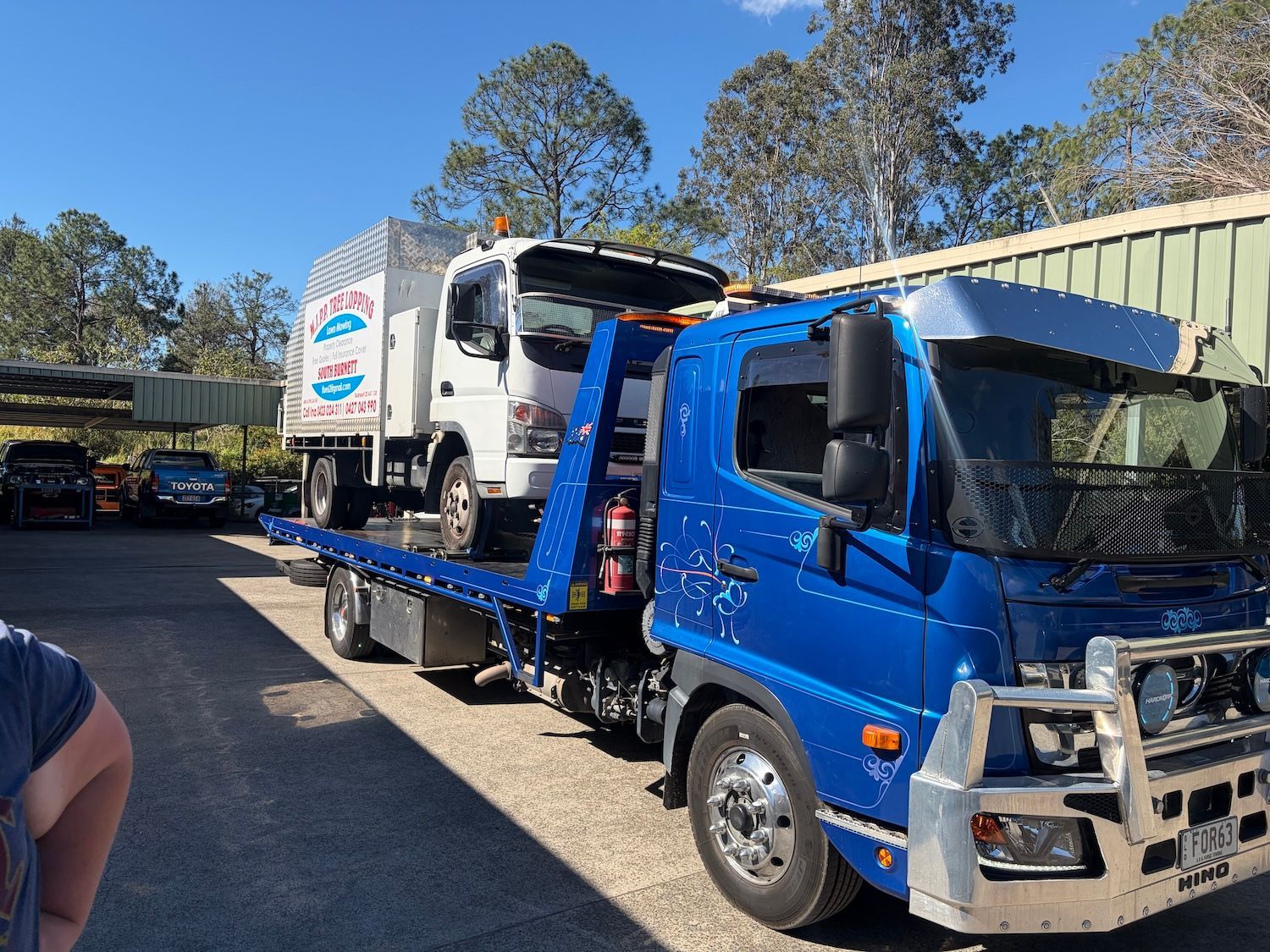 Blue Flatbed Tow Truck Parked Beside a Warehouse on a Wet Lot — A B & Forge Towing In Caboolture, QLD