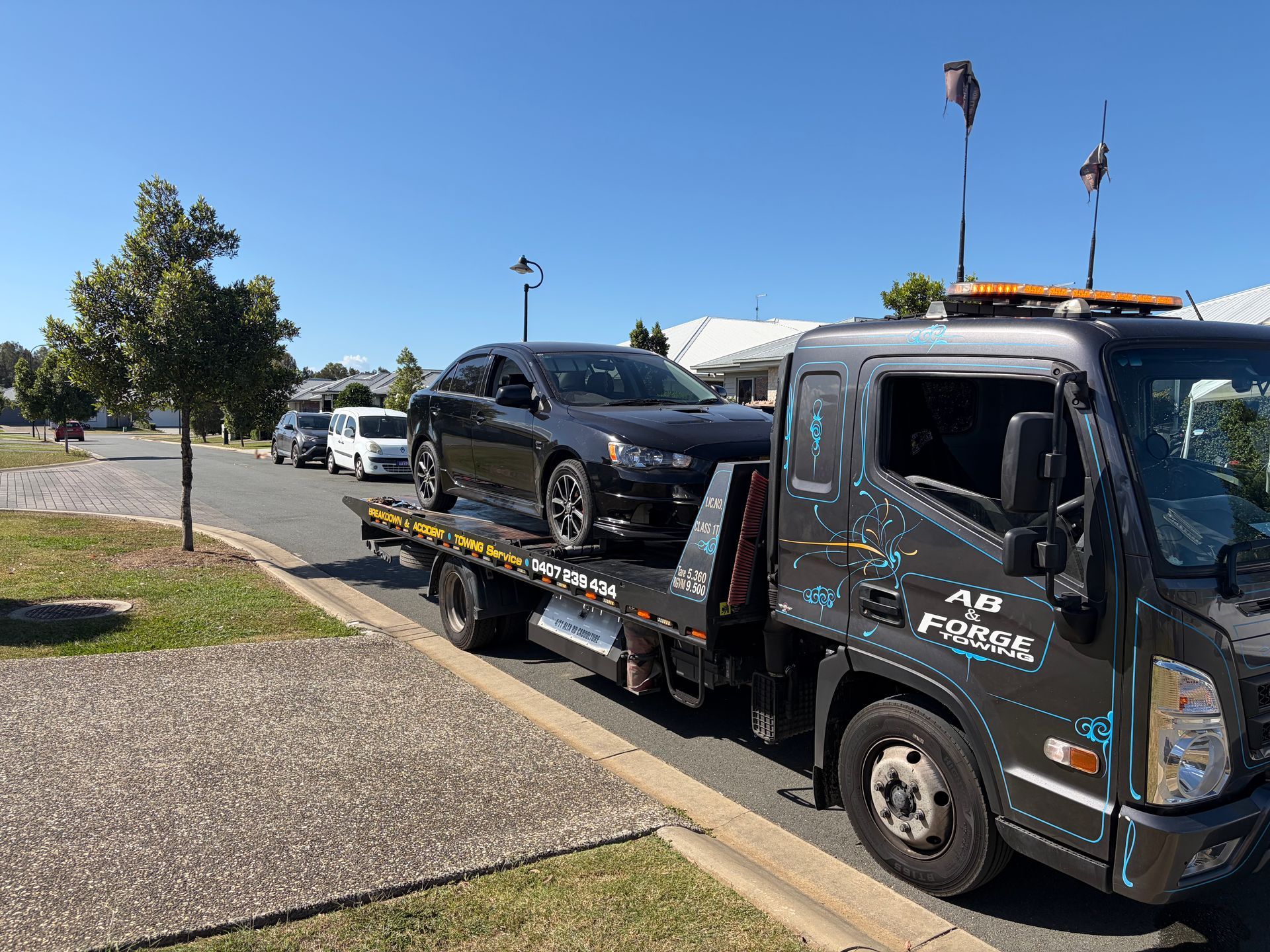 Tow Truck Hauling a Black Car on a Flatbed — A B & Forge Towing In Caboolture, QLD