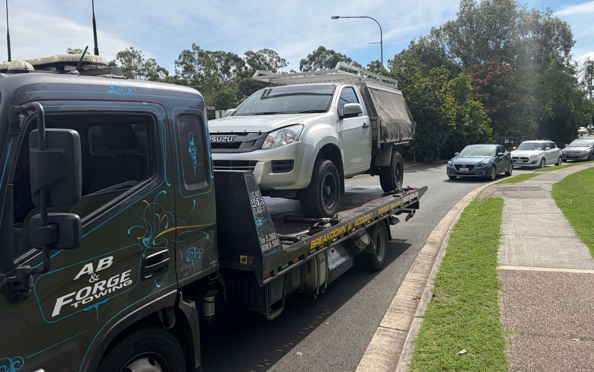 Tow Truck Hauling a Silver Ute on a Flatbed Along a Suburban Street — A B & Forge Towing In Caboolture, QLD