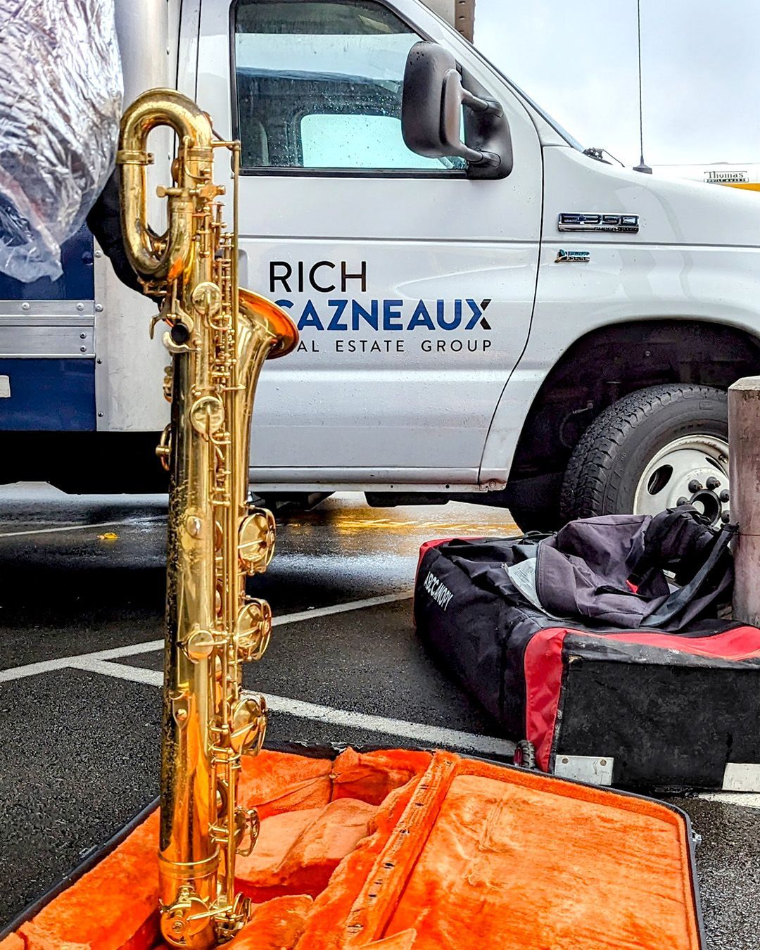 A saxophone sits in a case in front of a truck with the name Rich Cazneaux on it.