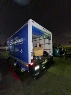 A man is sitting in the back of a blue and white truck.
