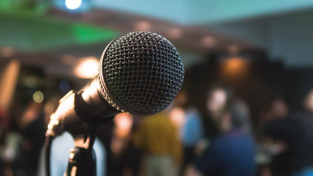 A microphone sitting on a stand in front of a crowd.