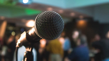 A microphone sitting on a stand in front of a crowd.