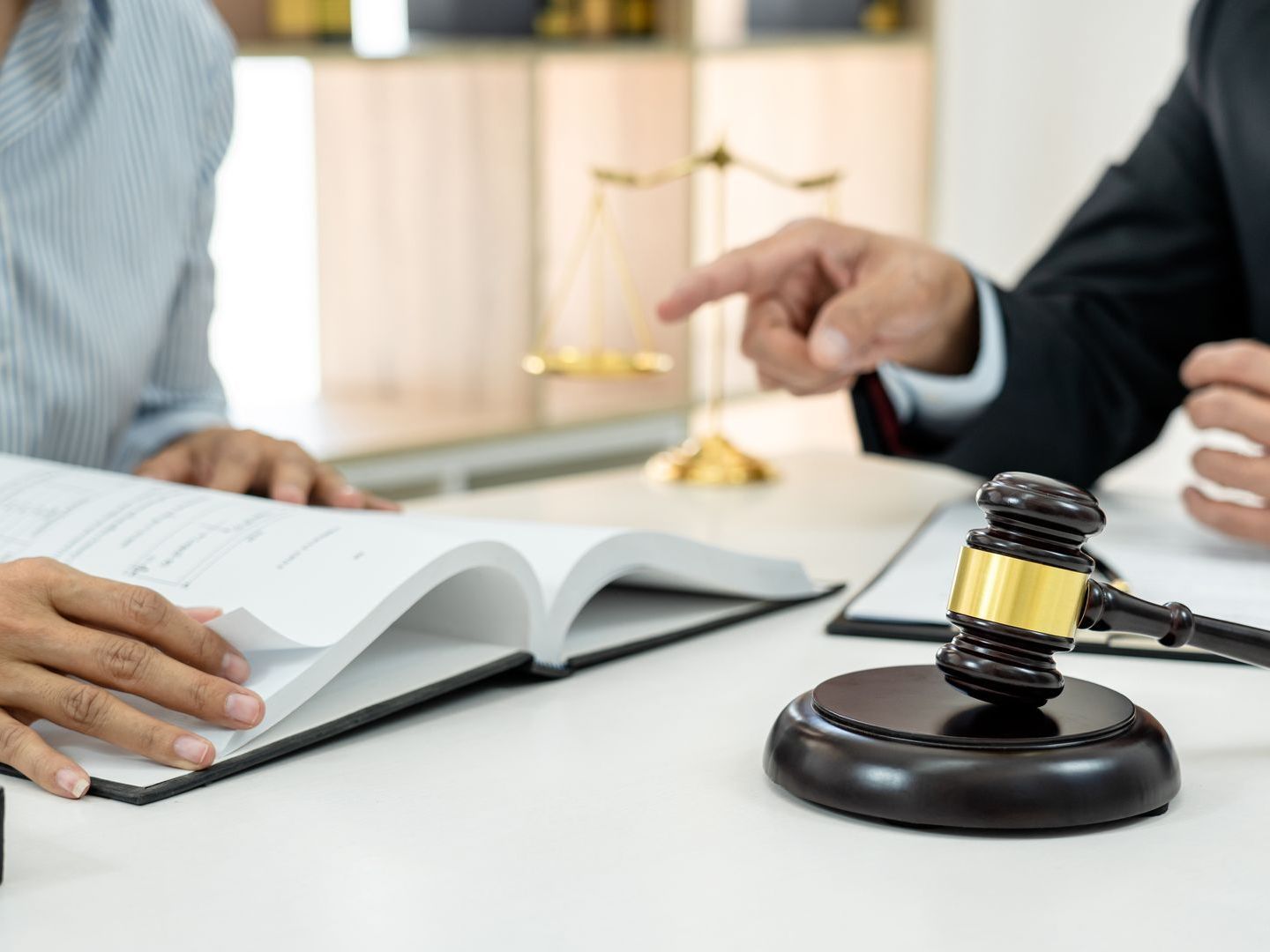 A man and a woman are sitting at a table with a book and a gavel.