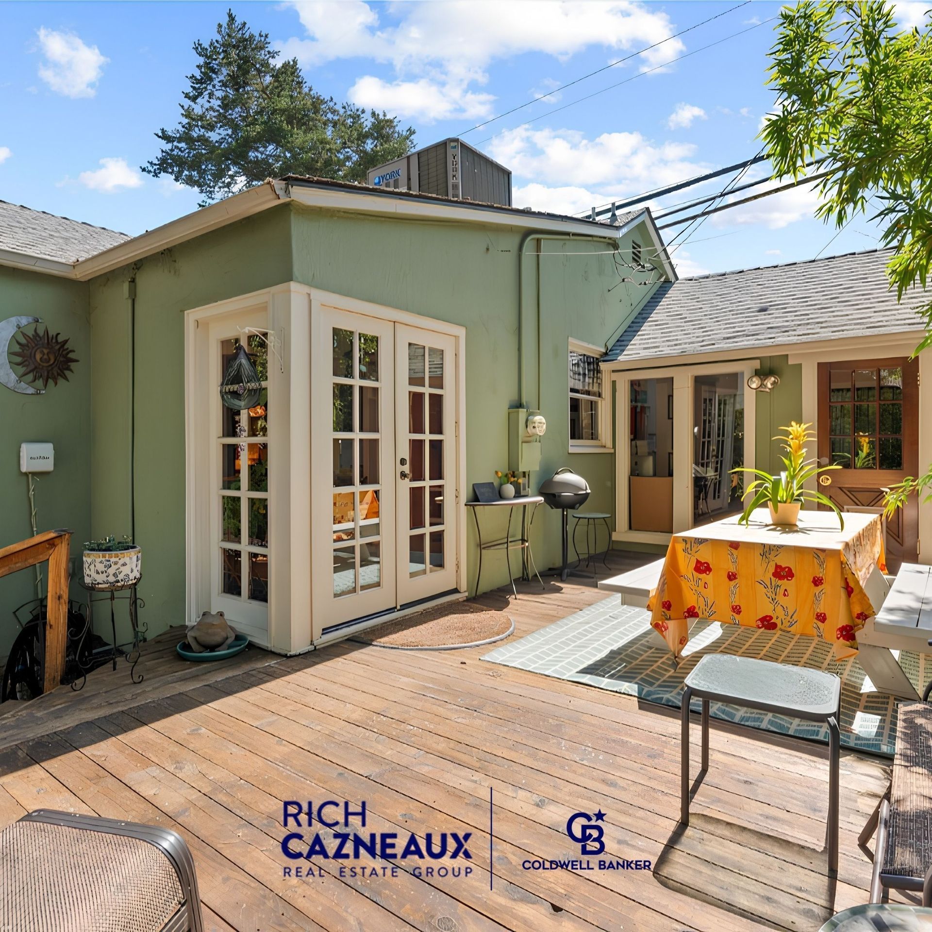 Wood deck with outdoor dining table, French doors, and green home exterior, with Rich Cazneaux of Coldwell Banker Sacramento logo.