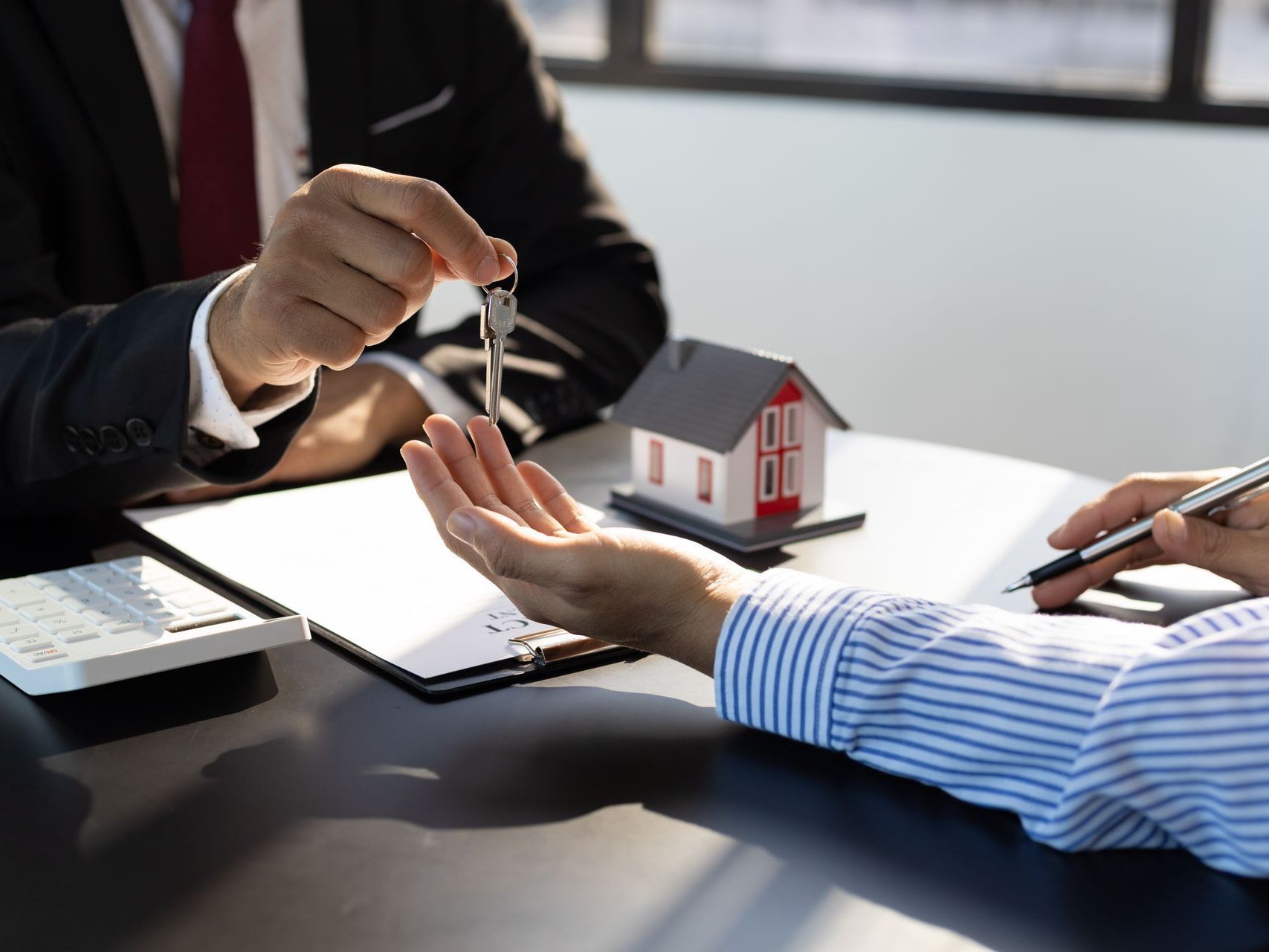 A man is giving a key to another man while sitting at a table.