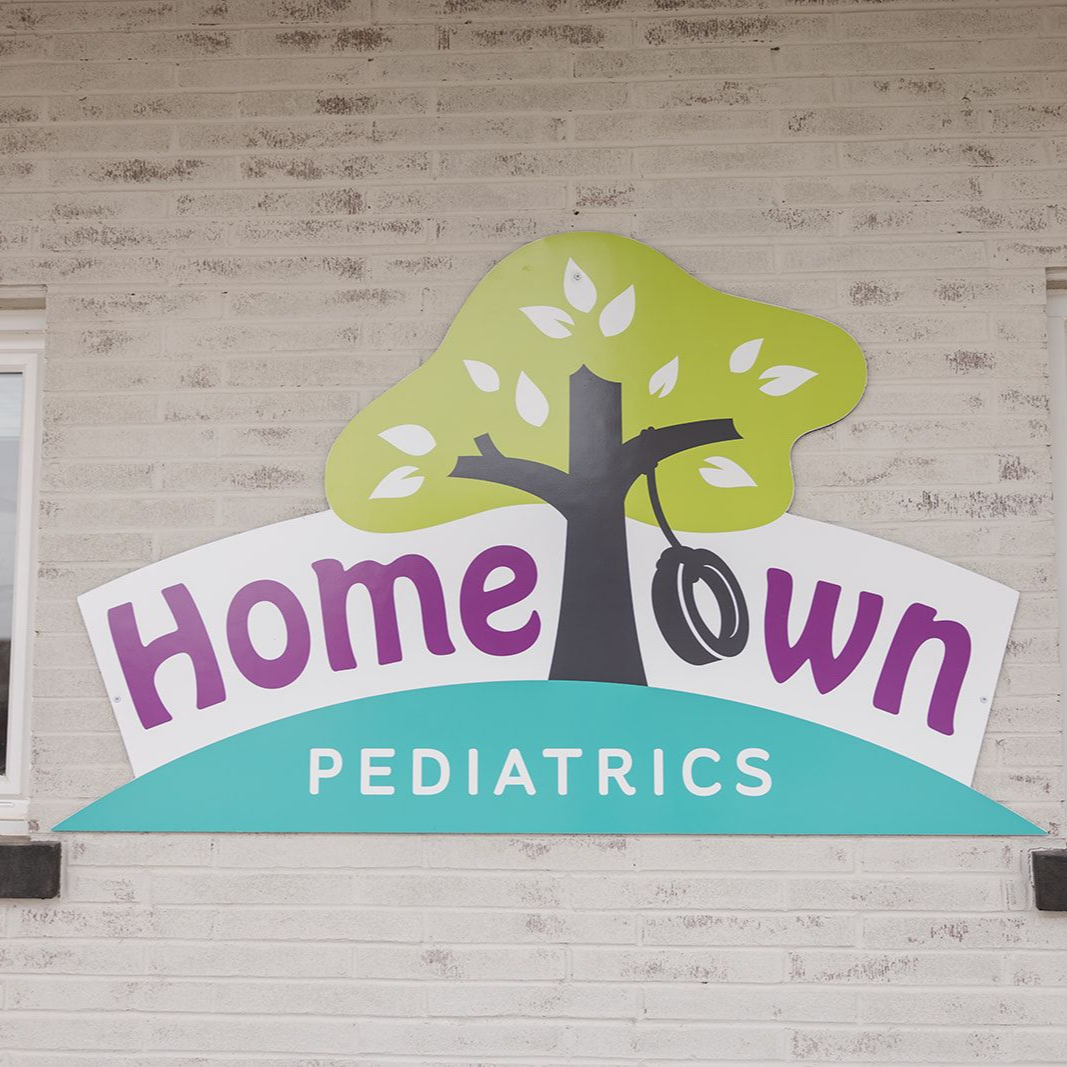 Sign for Hometown Pediatrics: tree logo above text on a brick building.