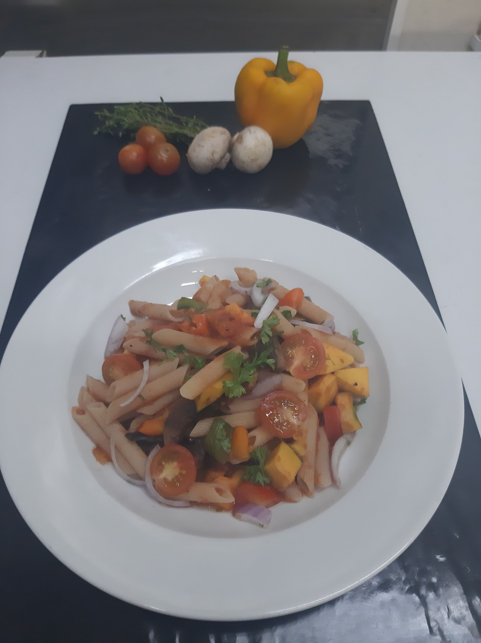 A white china plate with a bowl of Pasta and Vegetables