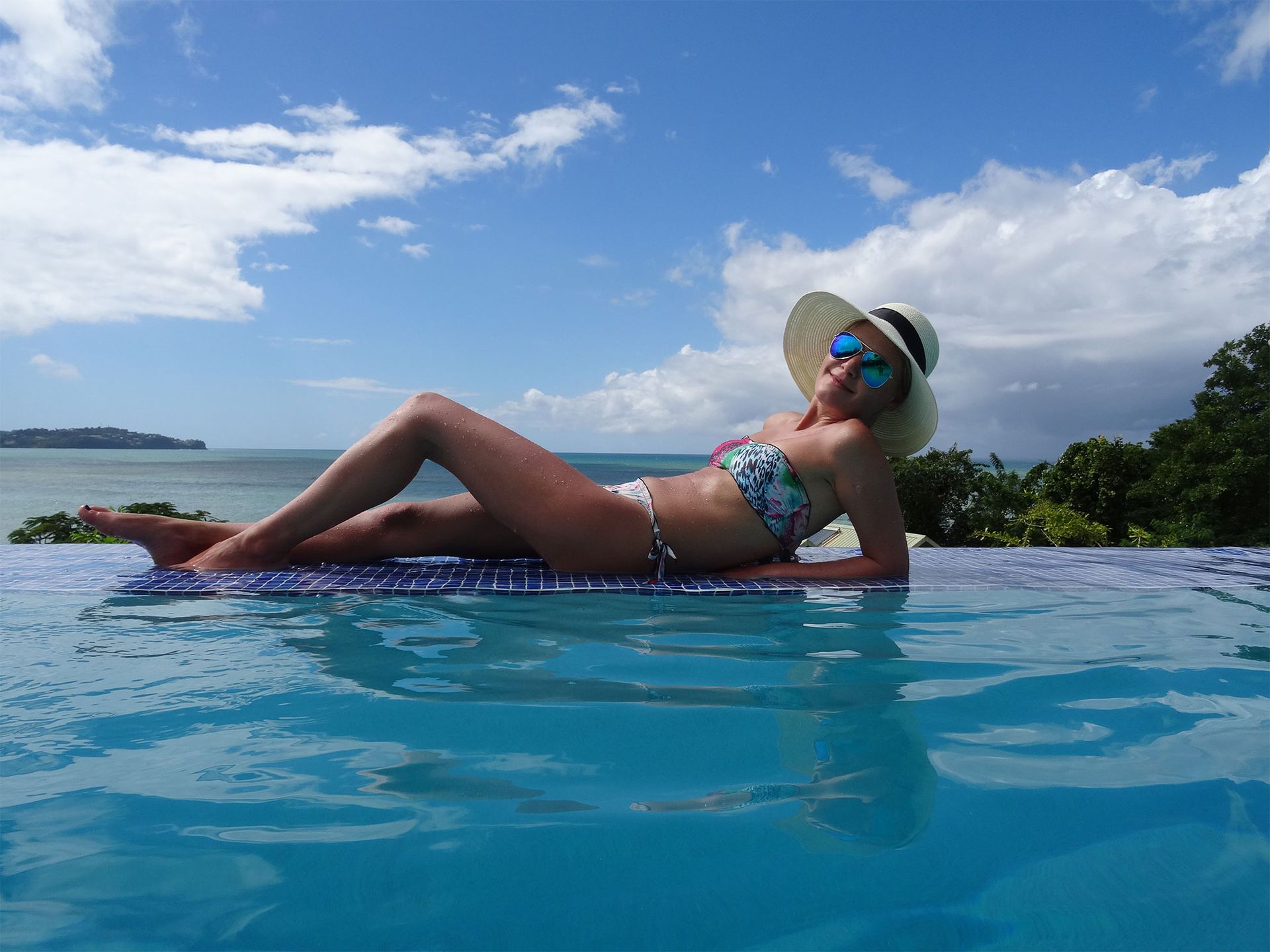 Girl lying on the edge of the pool wearing a sunhat