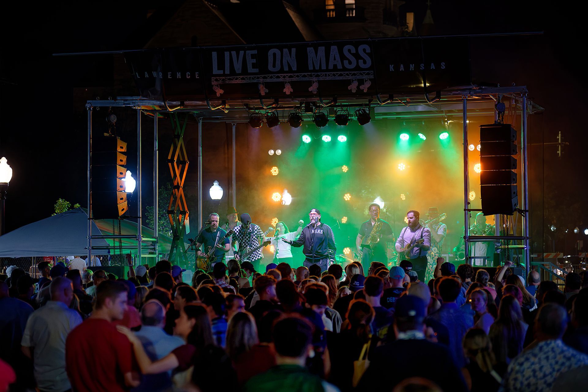Outdoor concert stage with colorful lights and a crowd watching live music at night