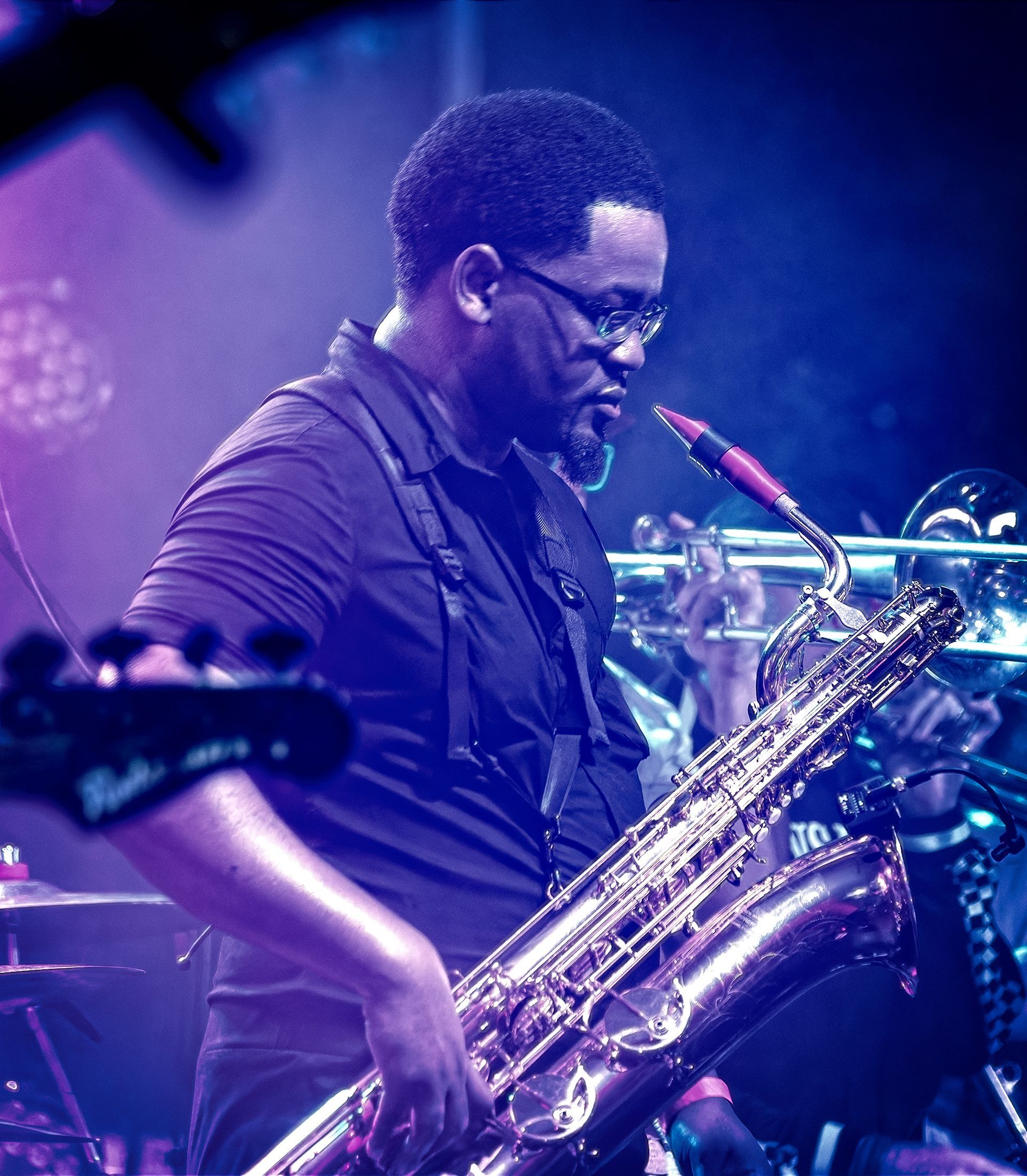 Musician playing a saxophone on a purple-lit stage
