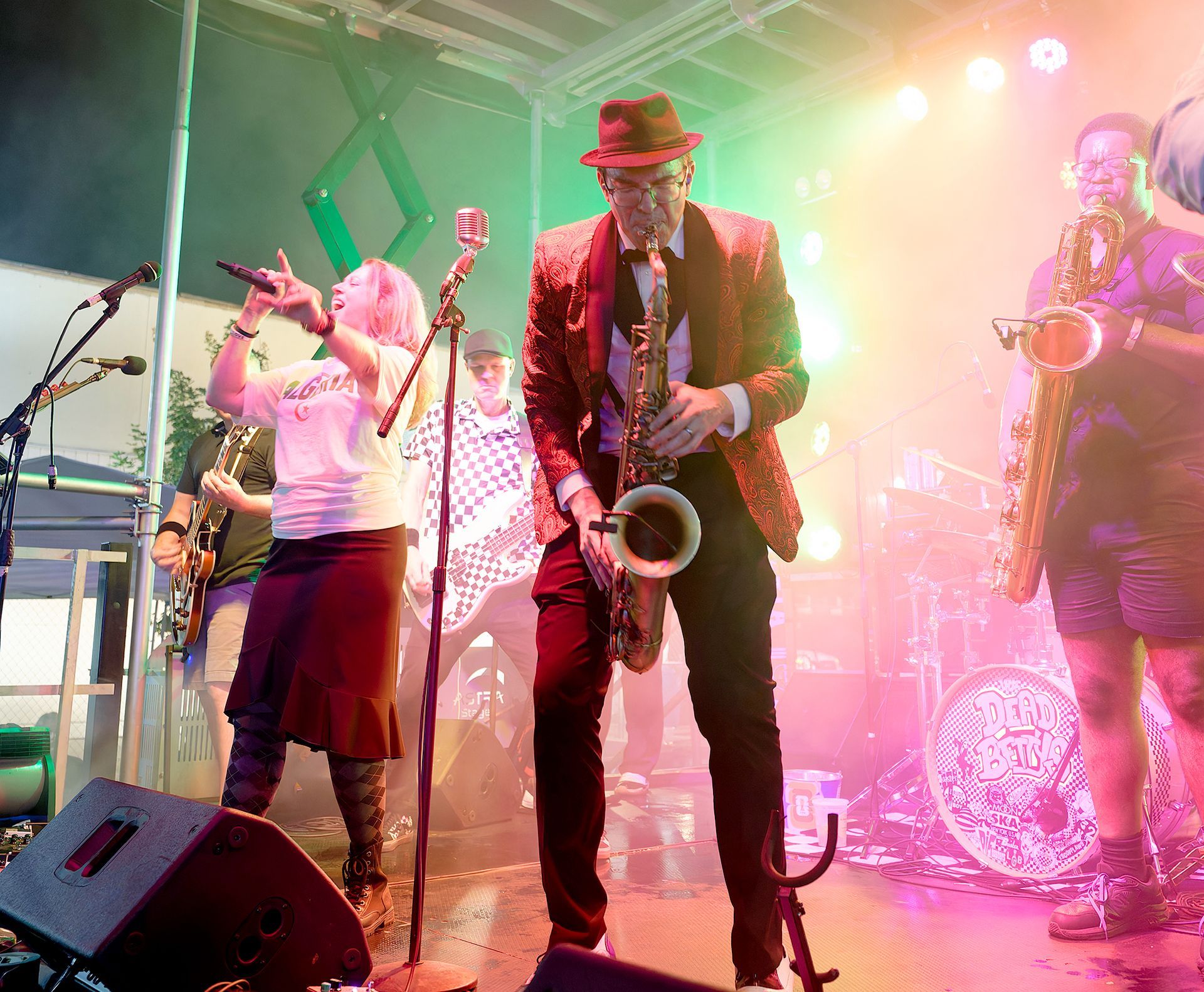 Live band performing on stage with colorful lights and a saxophone player in the center