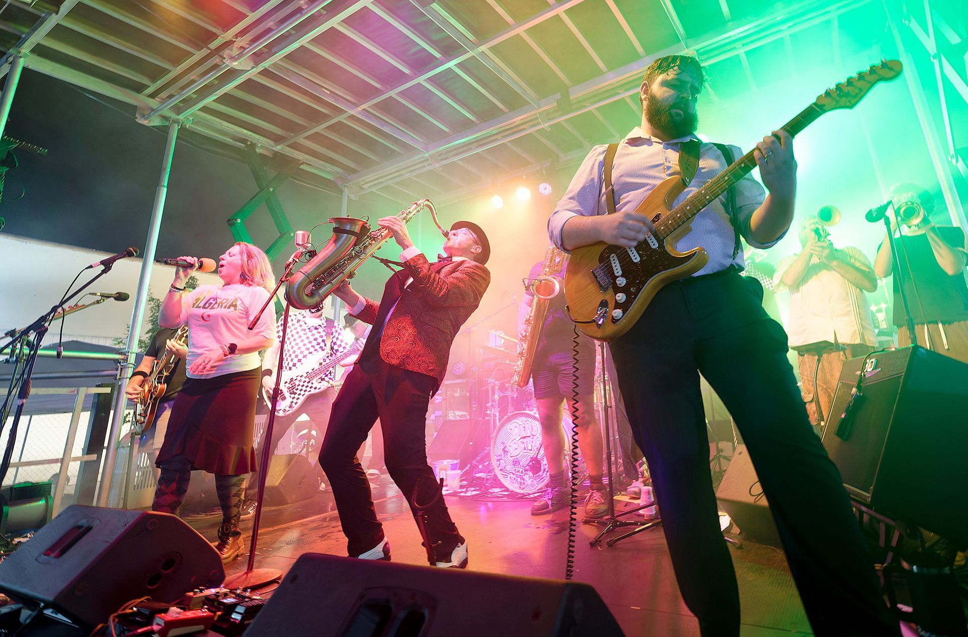 Live band performing on a brightly lit stage with colorful lights and guitars
