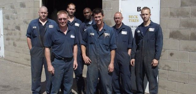 Beck Tire employees in navy uniforms standing outside a building, smiling at the camera.