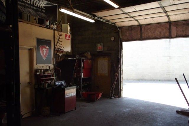 Inside a garage workshop with tools and equipment; bright open doorway on the right.