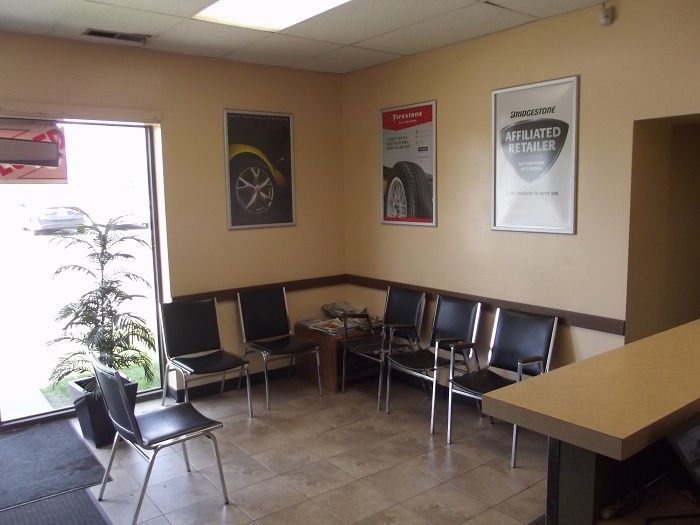 Empty waiting room with chairs, posters on beige walls, and a small table near a window.