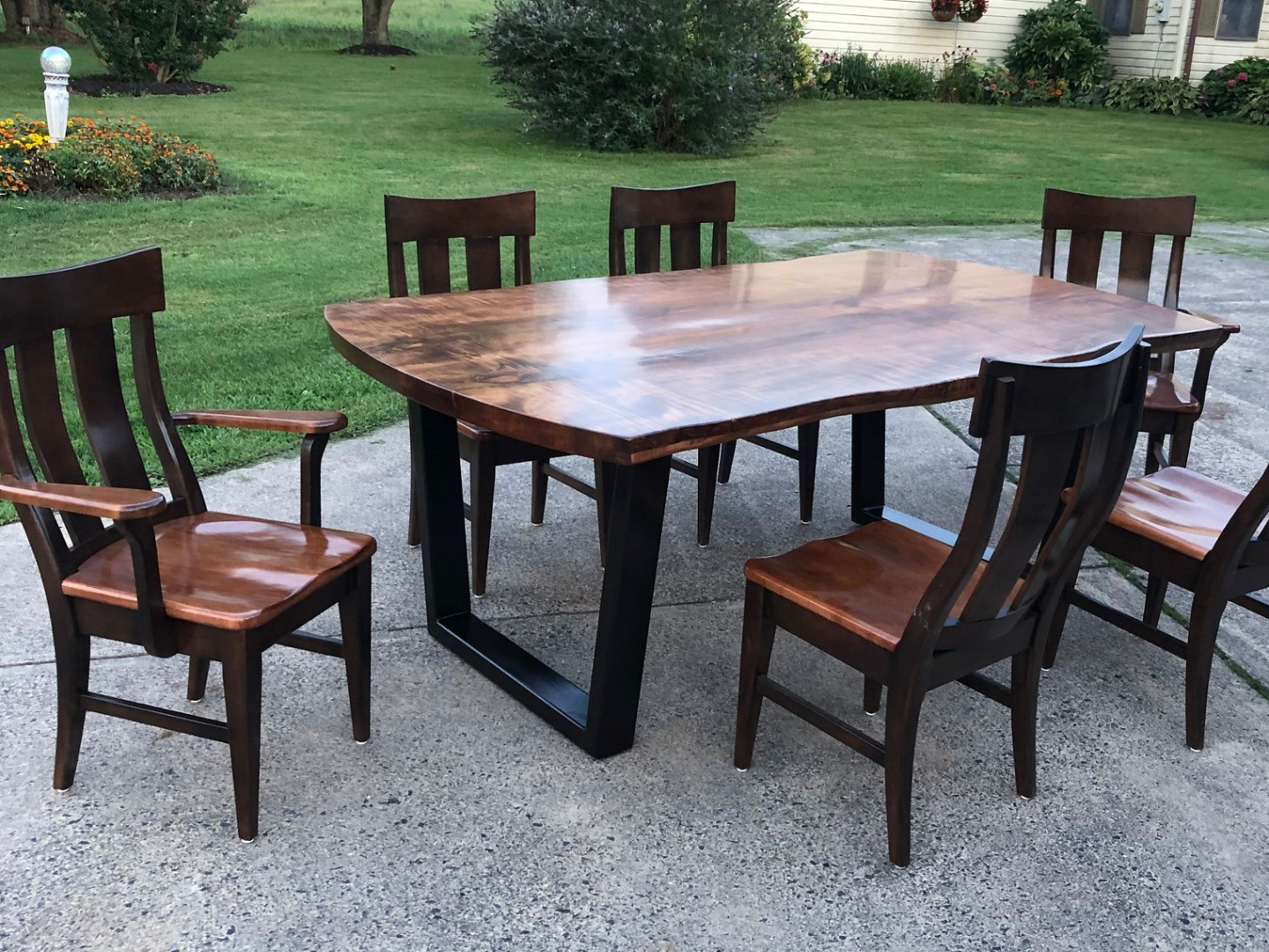 A wooden table and chairs are sitting on a concrete patio.