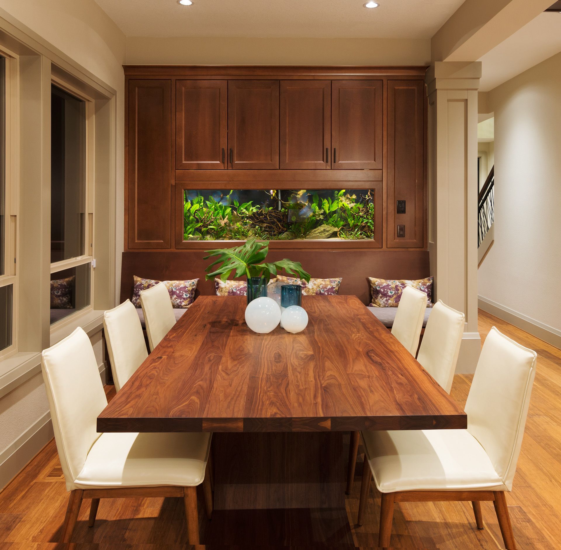 A dining room with a long wooden table and white chairs