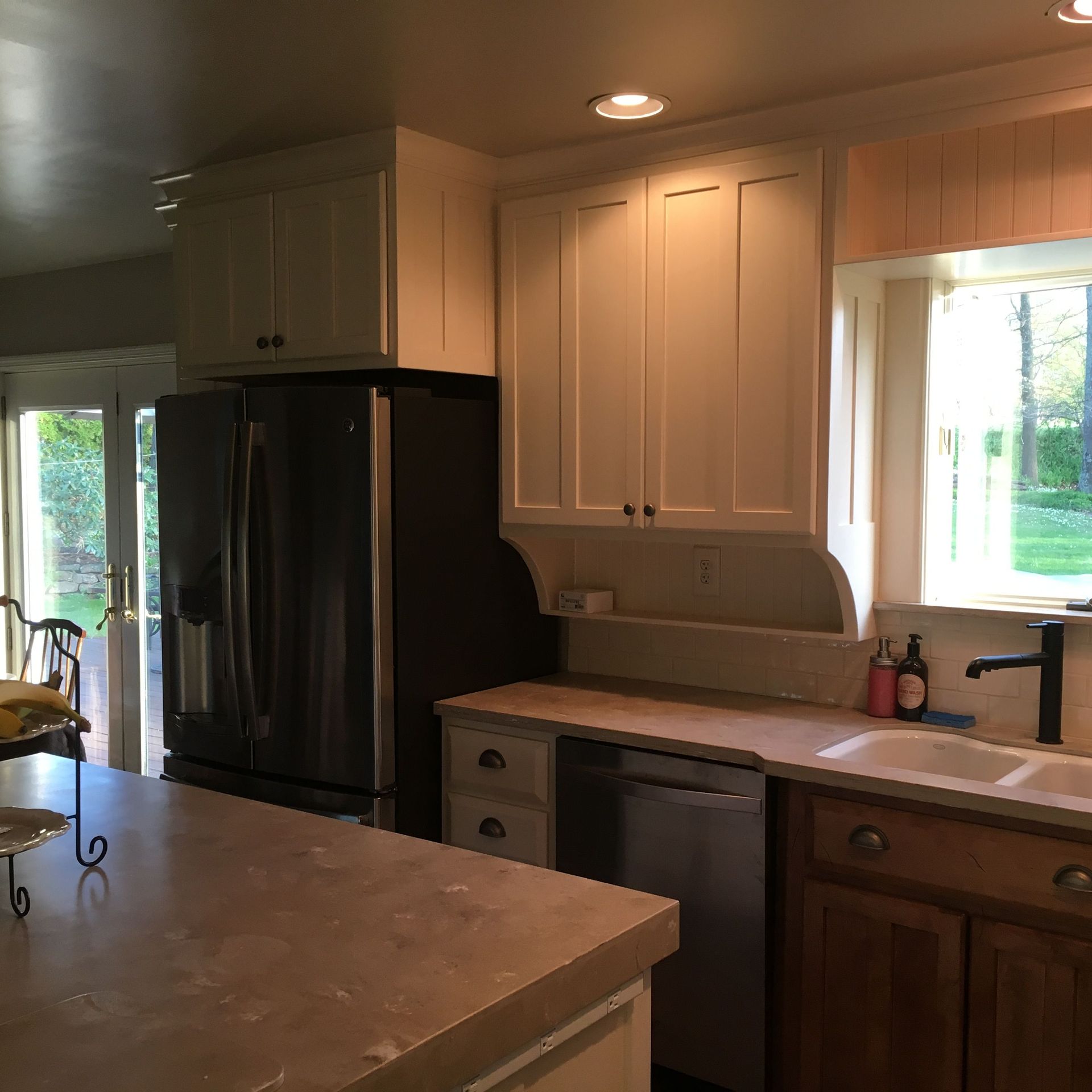 A kitchen with white cabinets and a black refrigerator