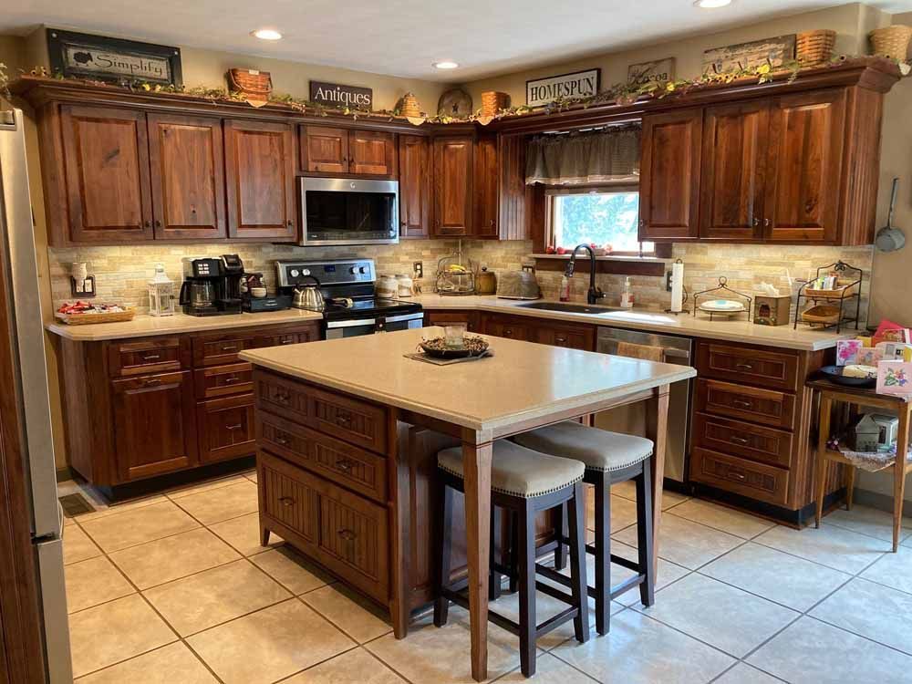A kitchen with wooden cabinets , granite counter tops , stainless steel appliances and a large island.