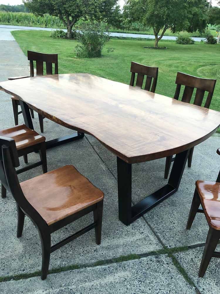 A wooden table and chairs are sitting on a concrete patio.