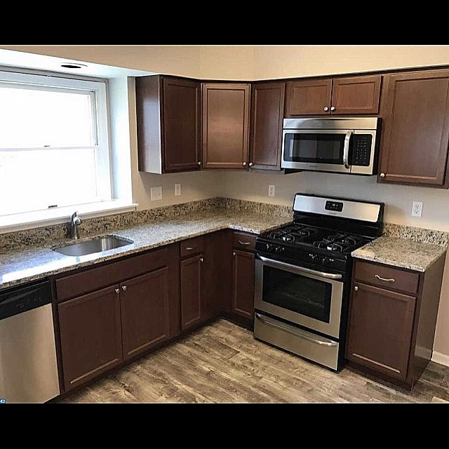 Modern kitchen with dark cabinets, stainless steel appliances, granite counters, and a window over the sink