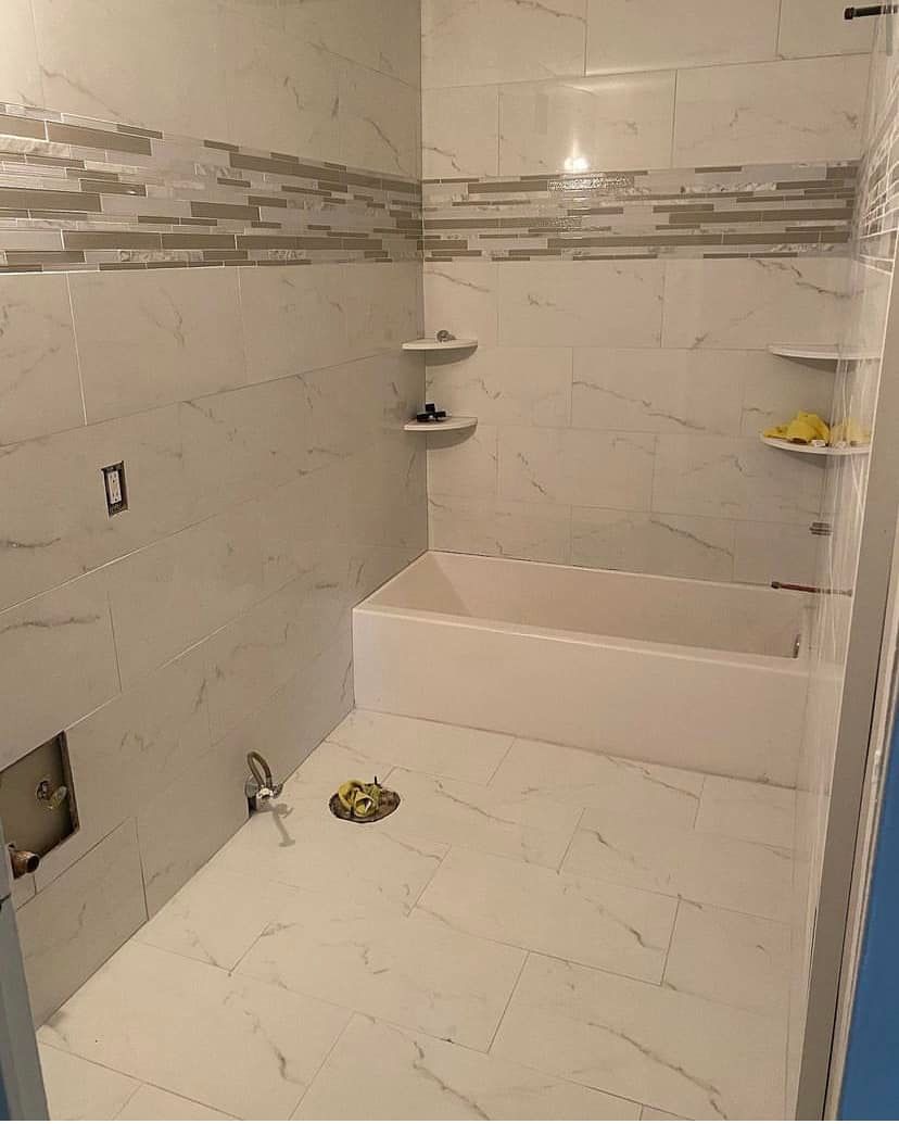 Small tiled shower under construction with recessed shelves and a built-in bench.