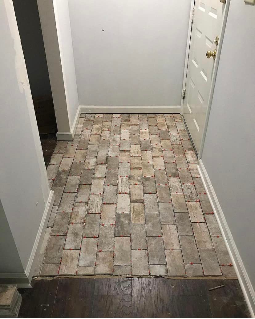 Narrow hallway with a patterned tile floor, light gray walls, and a white door at the end.