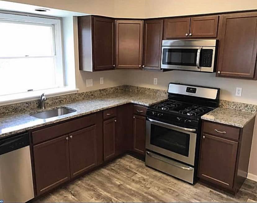 Modern kitchen with dark wood cabinets, stainless steel appliances, granite counters, and a window over the sink