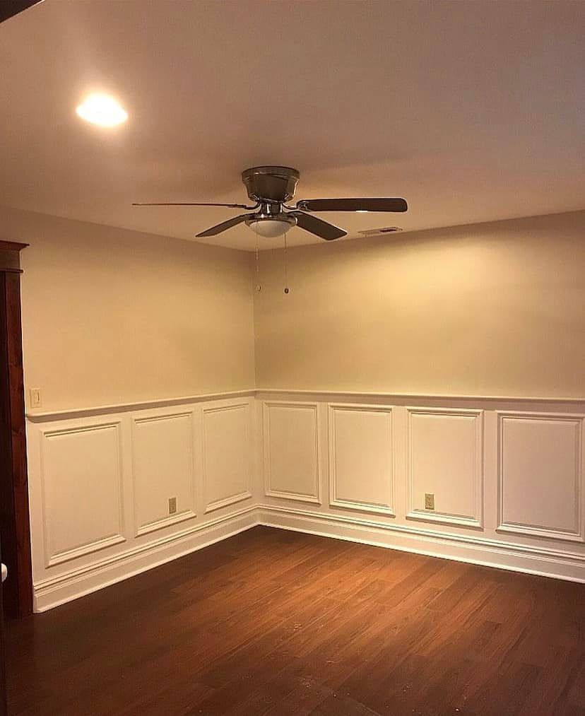 Empty room with white wainscoting, dark wood floor, ceiling fan, and recessed light