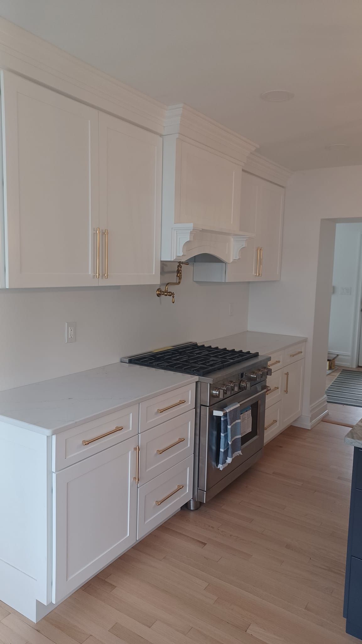Bright modern kitchen with white cabinets, stainless stove, and light wood flooring
