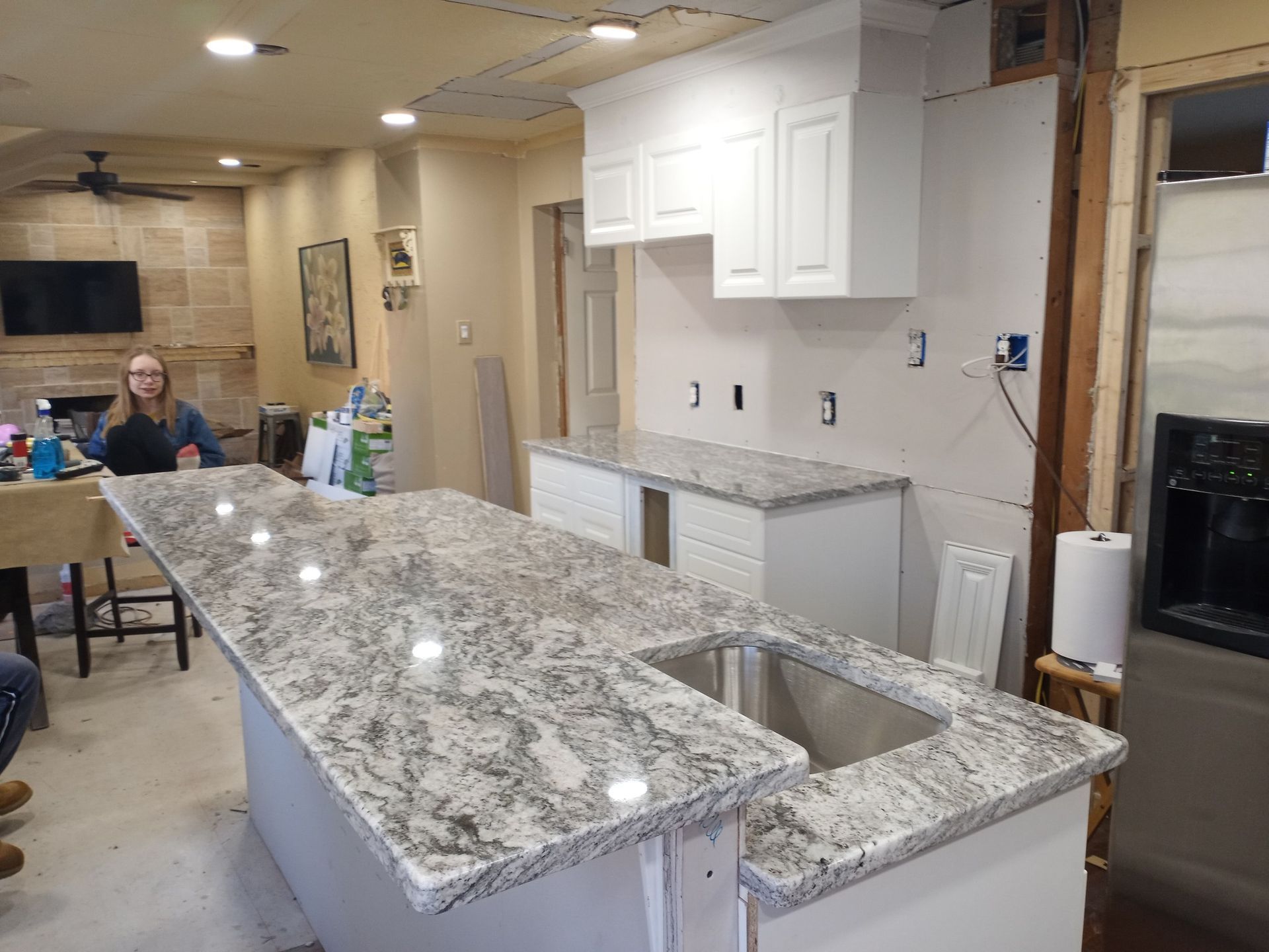 Kitchen renovation with granite island countertop and white cabinets in a partially finished room