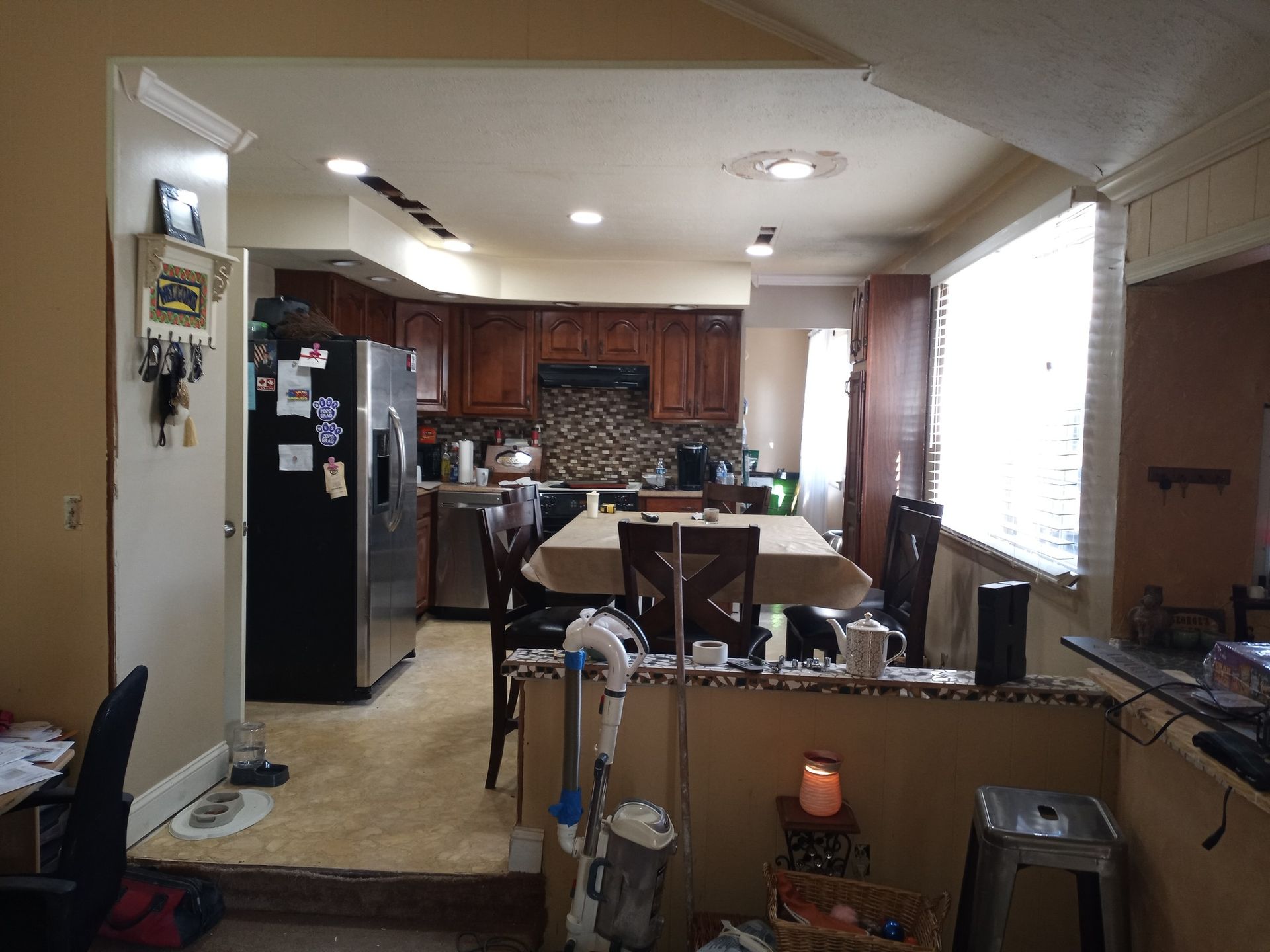 Kitchen and dining area with dark wood cabinets, white walls, and a black refrigerator.