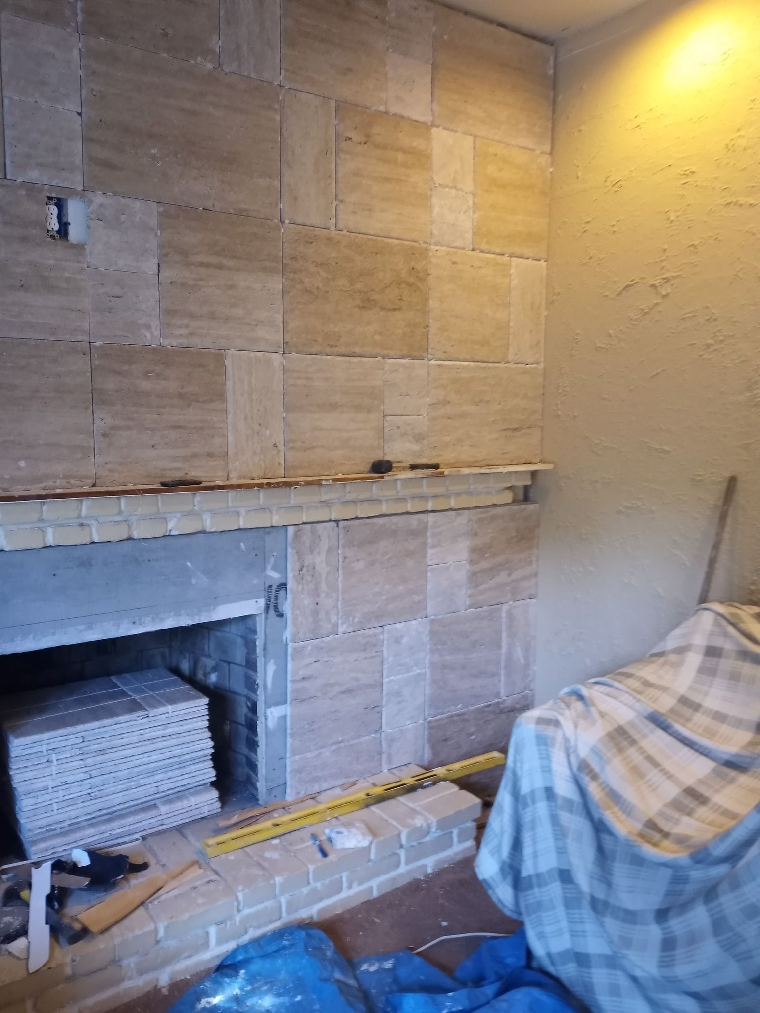 Bathroom with stone-tiled wall, small fireplace opening, and a person in a plaid shirt sitting on the right.
