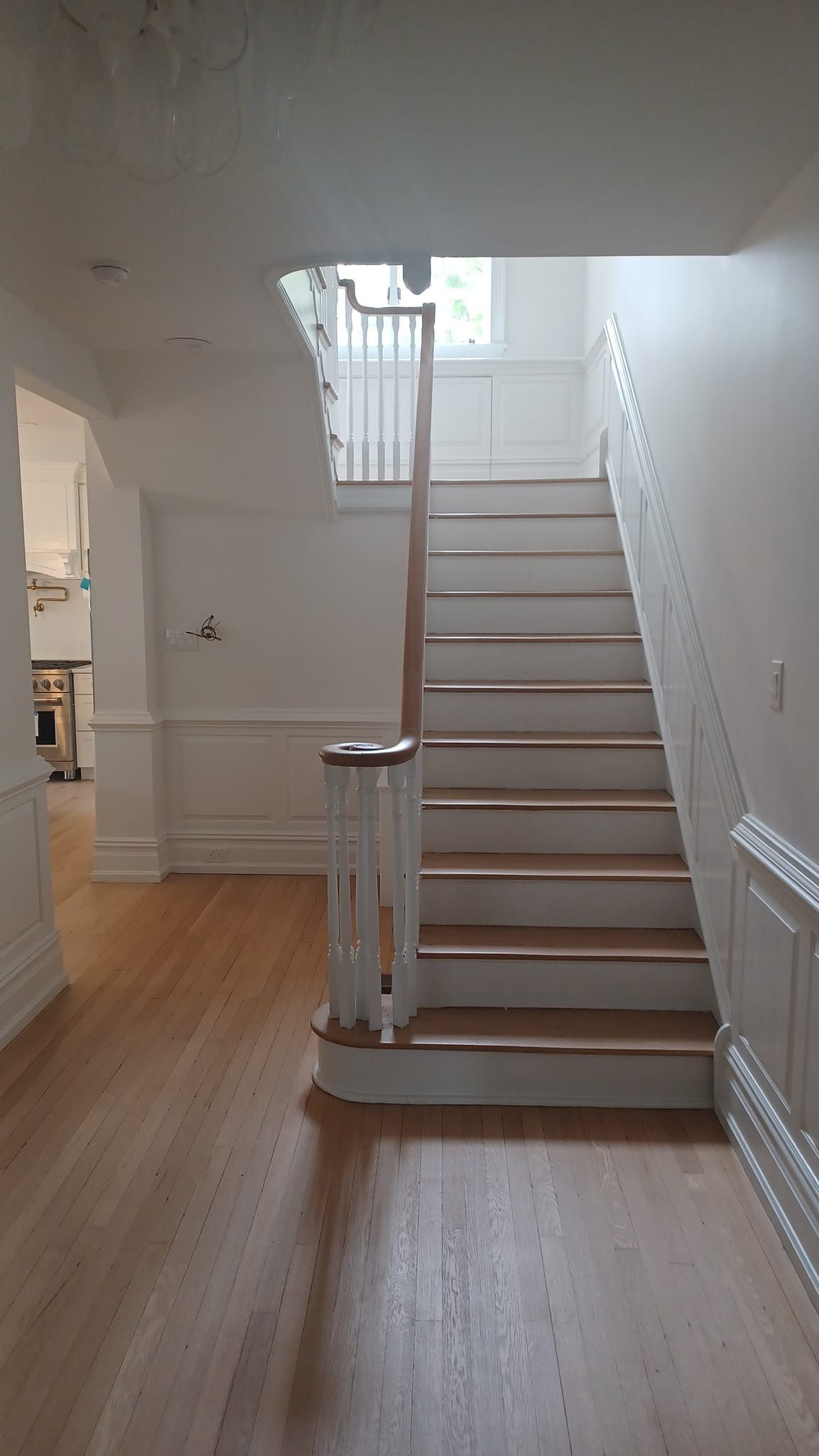 Bright hallway with wooden floor and carpeted staircase lit by a skylight
