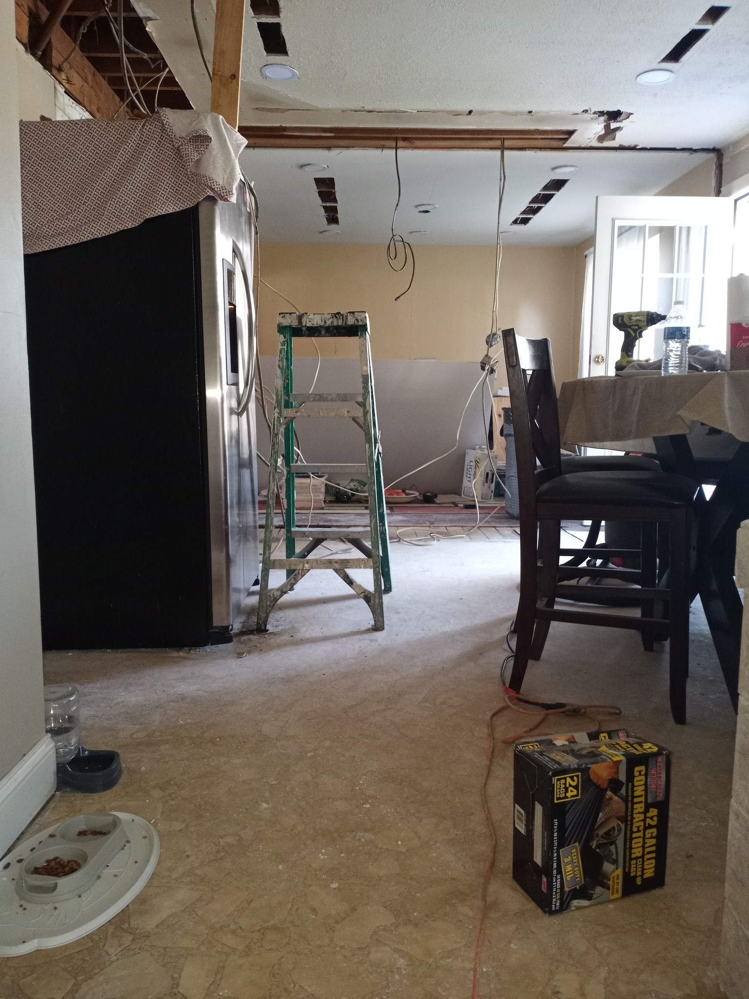 Partially renovated room with ladders, exposed ceiling, and construction tools.