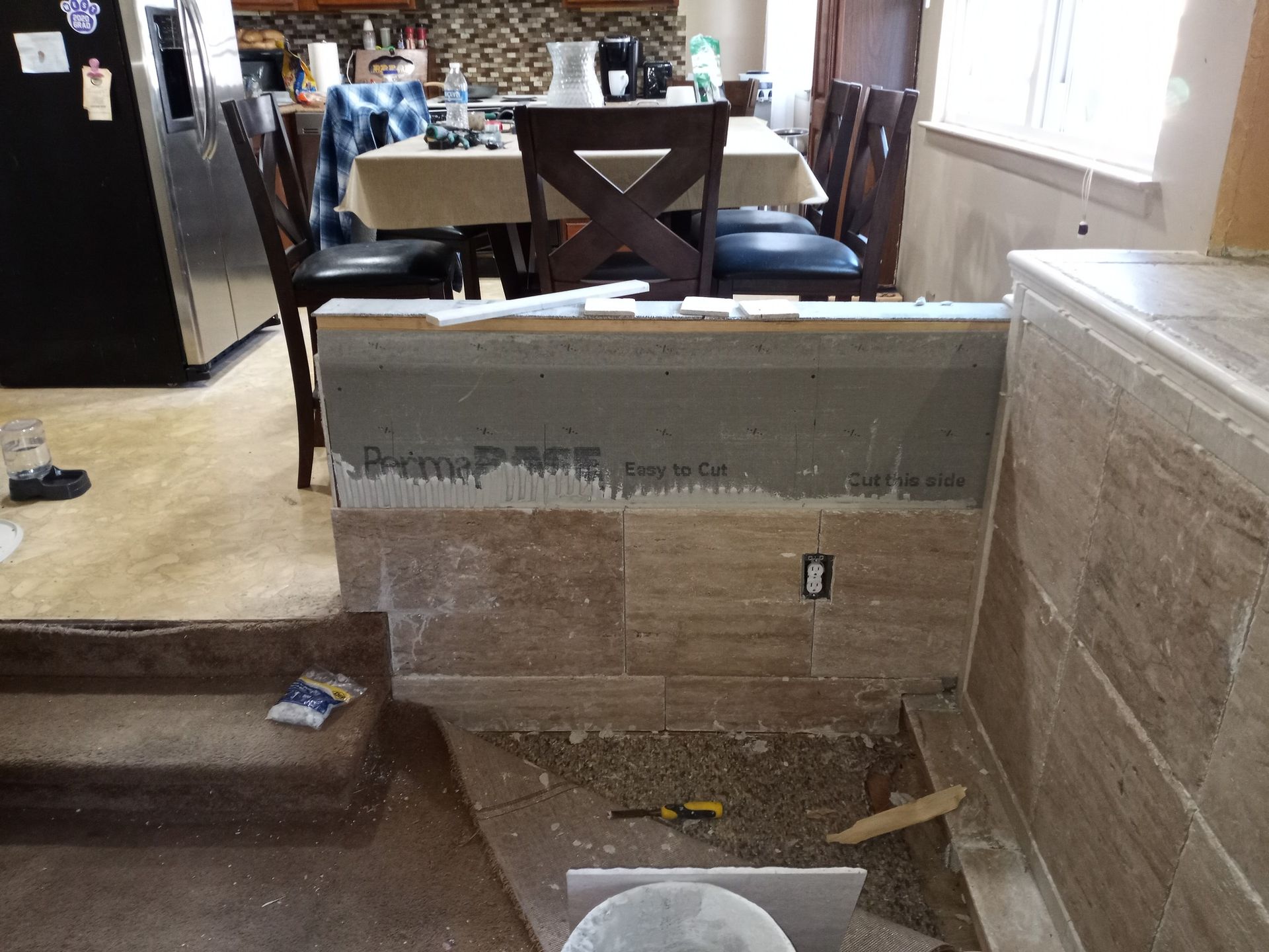 Damaged living room with cracked wall, exposed debris, and dining table in background