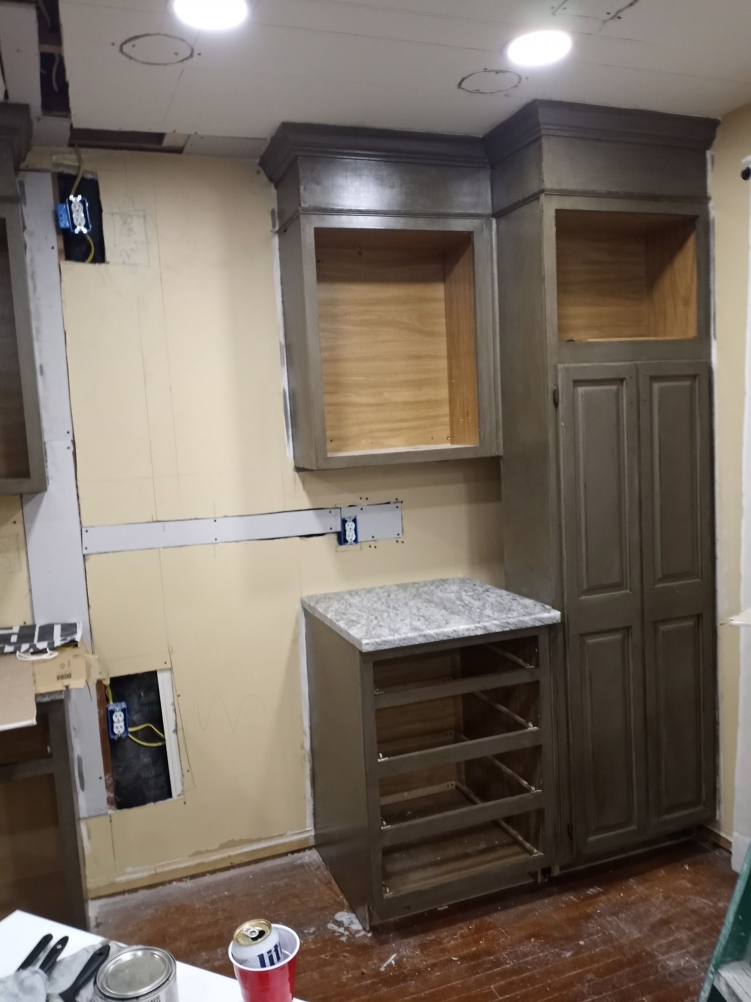 Partially renovated room with cabinets, countertop, and exposed wall wiring